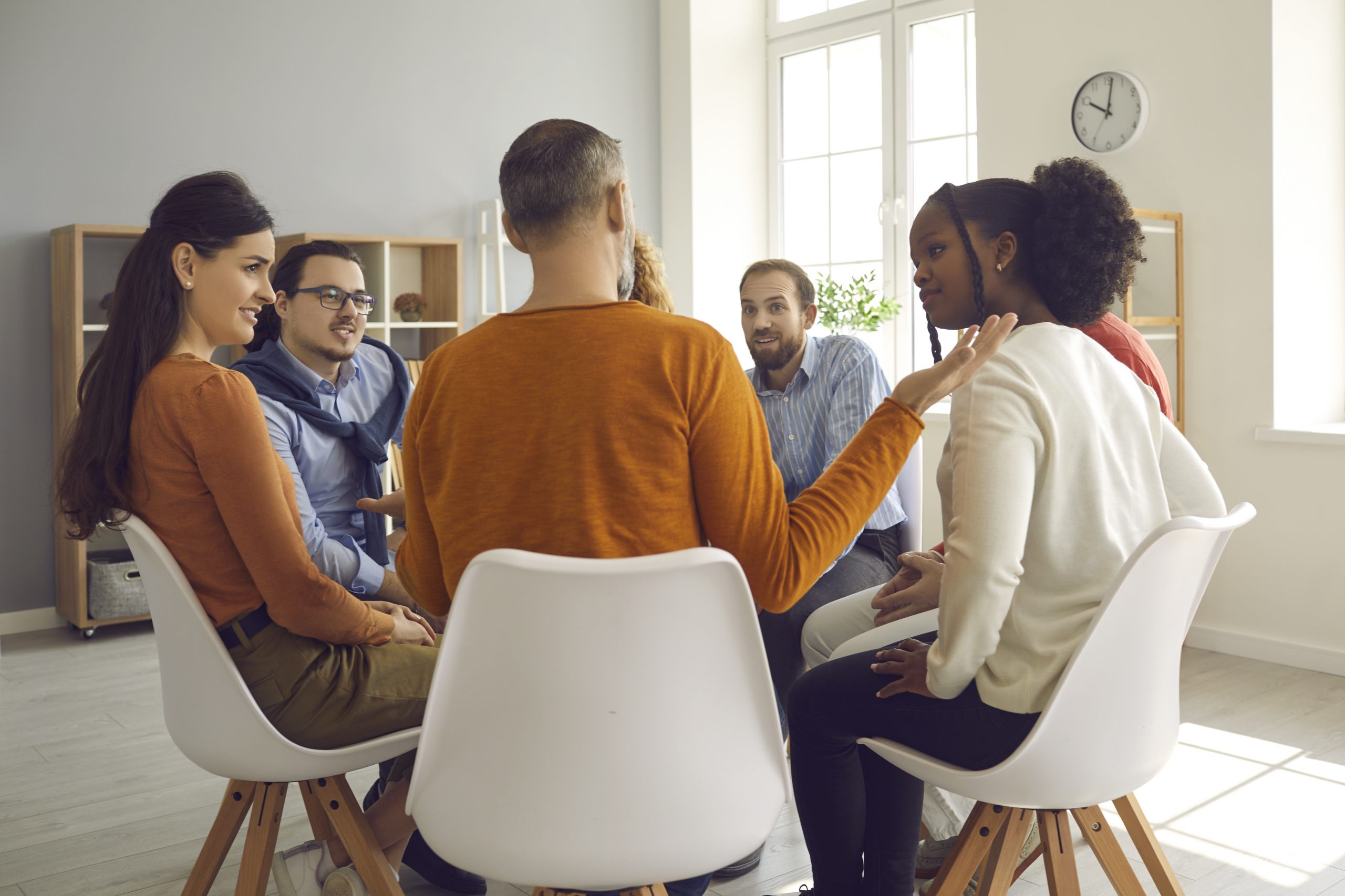 Close up rear view on people group sitting in circle discussion at modern office