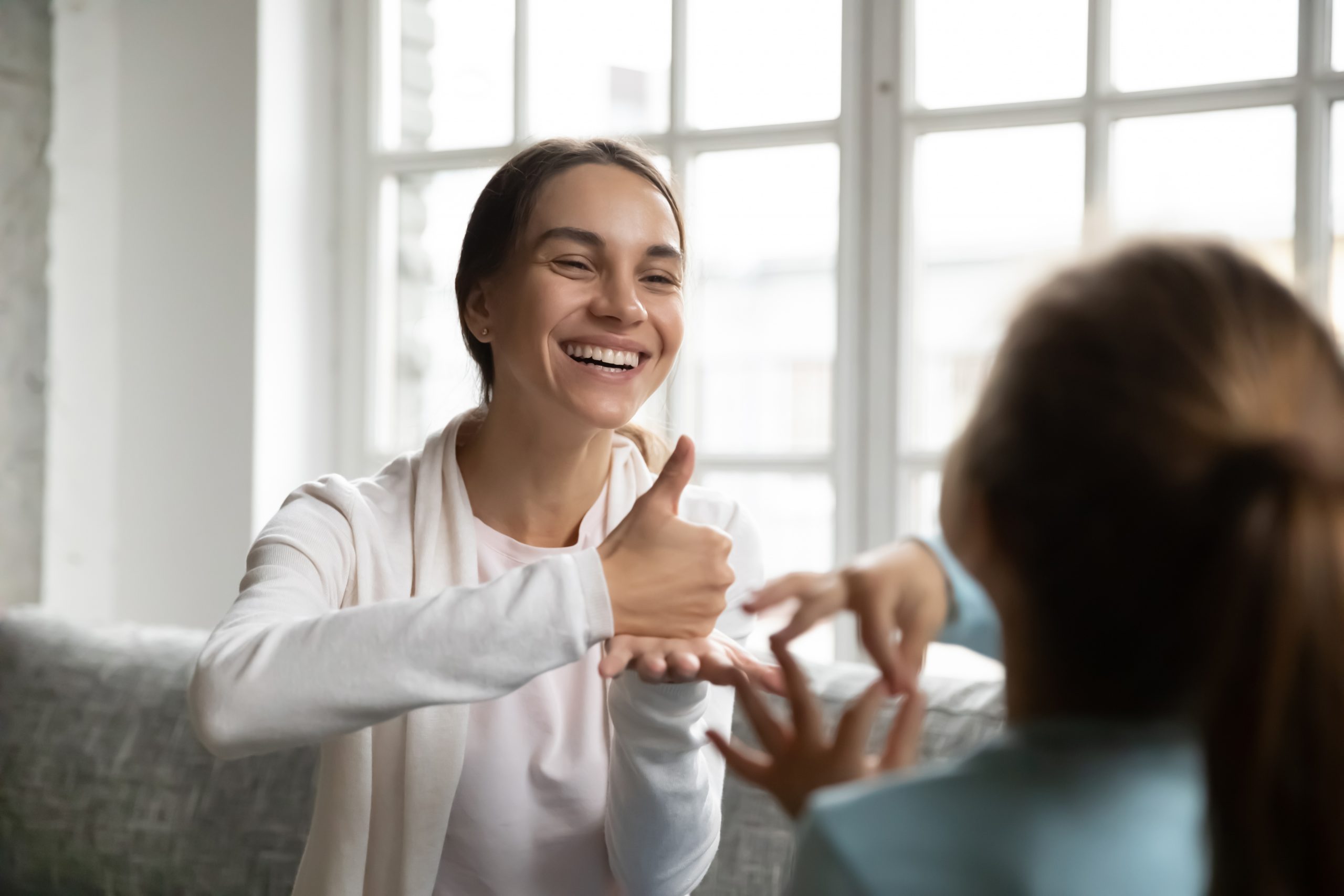 Smiling Caucasian woman learn sign language with little kid